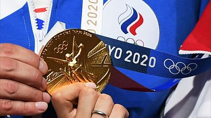 L'escrimeuse Sofia Pozdniakova brandit sa médaille d'or après son sacre olympique dans l'épreuve de sabre, à Chiba, près de Tokyo (Japon), le 26 juillet 2021. (RAMIL SITDIKOV / SPUTNIK / AFP)