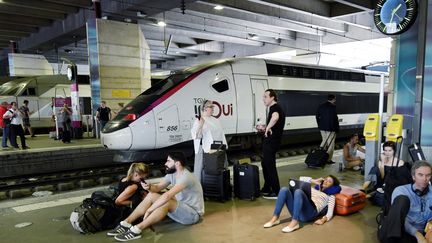 Des voyageurs attendent à la gare Montparnasse, le 27 juillet 2018 à Paris. (GERARD JULIEN / AFP)