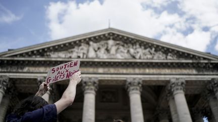 Une personne avec une pancarte "soutien aux gilets noirs", le 12 juillet 2019 à Paris.&nbsp; (KENZO TRIBOUILLARD / AFP)