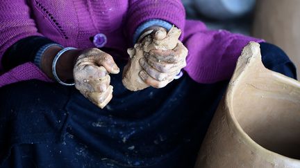 Sabiha Ayari travaille dans des conditions ardues. Elle bêche et tire du sol un seau d'argile grise dans laquelle elle façonne des pots, des plats et des poupées. (FETHI BELAID / AFP)