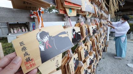 Un prêtre du sanctuaire d'Iwashizu montre le personnage de Black Jack peint sur des tablettes votives en bois dans la ville de Takarazuka, préfecture de Hyogo, au Japon, le 8 février 2023. (KENICHI UNAKI / YOMIURI / AFP)