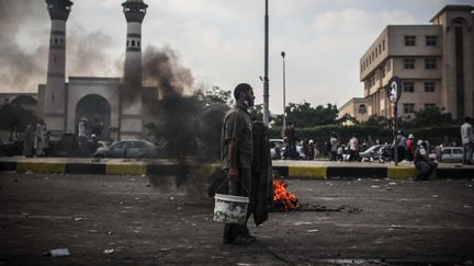 Un homme devant un feu sur la place Al-Adawiya au Caire, apr&egrave;s les r&eacute;pressions contre les partisans de Mohamed Morsi, le 27 juillet 2013. (CITIZENSIDE.COM / AFP)