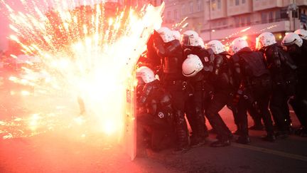 Des policiers turcs se prot&egrave;gent des feux d'artifices tir&eacute;s par des manifestants &agrave; Istanbul (Turquie), le 7 d&eacute;cebre 2013. (BULENT KILIC / AFP)