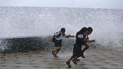 Des &eacute;coliers s'amusent avec les vagues qui s'&eacute;crasent contre la jet&eacute;e &agrave; Bombay (Inde), le 25 juin 2013. (VIVEK PRADASH / REUTERS)