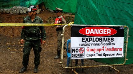 Un policier se tient devant l'entrée de la grotte de Tham Luang (Thaïlande), où sont piégés douze adolescents accompagnés de leur entraîneur, le 8 juillet 2018.&nbsp; (SOE ZEYA TUN / Reuters)