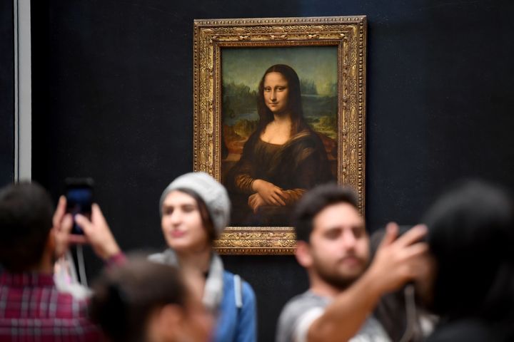 Des visiteurs se prennent en photo devant "La Joconde" au musée du Louvre (ERIC FEFERBERG / AFP)
