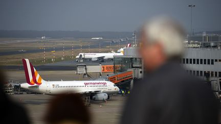 Un homme regadre un avion de Germanwings sur l'a&eacute;roport de D&uuml;sseldorf le 24 mars 2015. (SASCHA SCHUERMANN / AFP)