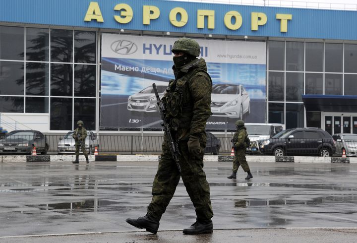 Un homme arm&eacute; patrouille devant l'a&eacute;roport&nbsp;Simferopol, en Crim&eacute;e.&nbsp; (VIKTOR DRACHEV / AFP)