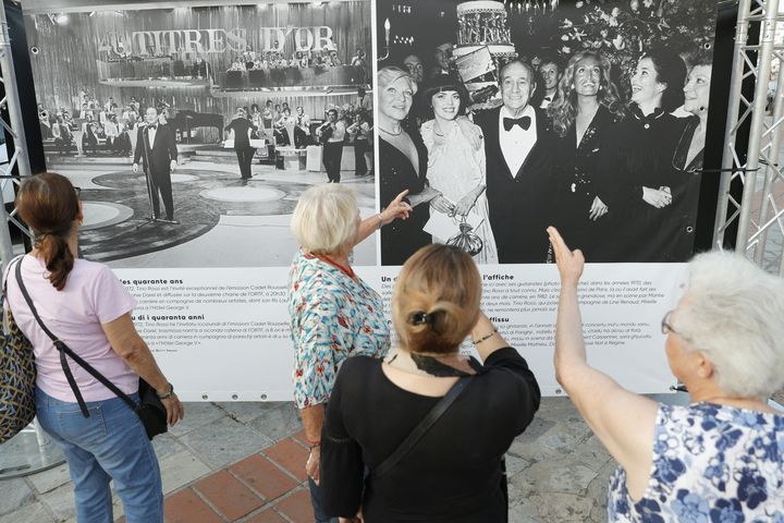 Des visiteurs contemplent les photographies de l'exposition consacrée à Tino Rossi à Ajaccio, inaugurée le 10 août 2023. (PASCAL POCHARD-CASABIANCA / AFP)