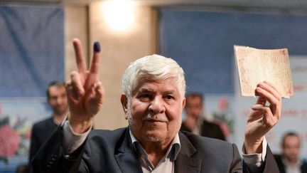 Alors que la veuve et la fille de l'ancien président iranien défunt, Akbar Hashemi Rafsandjani, ont quitté le pays pour la Grande Bretagne, son frère, Mohammad Hashemi brandit sa pièce d'identité devant les journalistes, après avoir déposé sa candidature à l'élection présidentielle au ministère de l'intéreiur, à Téhéran le 15 avril 2017.  (Fatemeh Bahrami/Anadolu Agency/AFP )