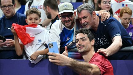 Le Tricolore Yacine Louati fait des selfies avec des supporters après le match opposant la France et la Slovénie, lors du dernier match de groupe du tournoi olympique, le 2 août 2024, à l'Arena Paris Sud. (NATALIA KOLESNIKOVA / AFP)