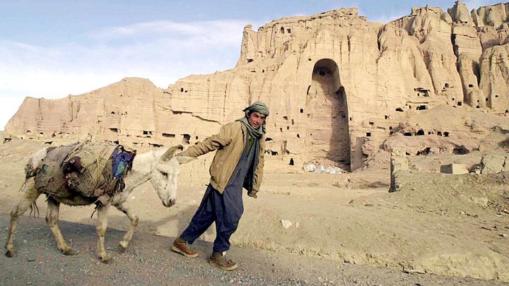 Un gar&ccedil;on tire son &acirc;ne, en 2002, devant l'emplacement o&ugrave; se trouvait l'un des bouddhas de Bamiyan, en Afghanistan, un an apr&egrave;s son dynamitage par les talibans. (JEWEL SAMAD / AFP)