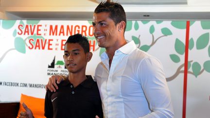 Cristiano Ronaldo (&agrave; droite) serre dans ses bras Martunis, un Indon&eacute;sien de 16 ans qui a surv&eacute;cu au tsunami de d&eacute;cembre 2004, le 26 juin 2013. (SONNY TUMBELAKA / AFP)