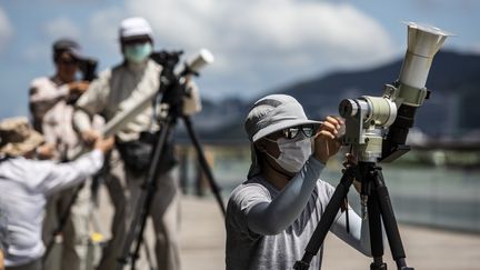 Comme d'autres astronomes amateurs, une femme prépare son télescope pour observer l'éclipse annulaire depuis une jetée, à Hong Kong. (ISAAC LAWRENCE / AFP)