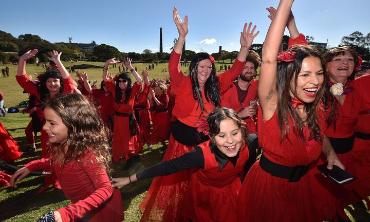 Des fans de Kate Bush vêtues de rouge célèbrent son tube "Wuthering Heights" ("Les Hauts de Hurlevent") en dansant durant un flashmob à Sydney le 13 juillet 2019. (PETER PARKS / AFP)