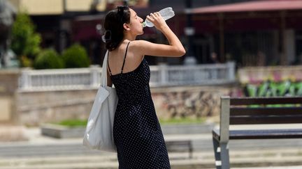 Une femme s'hydrate, à Skopje  (Macédoine), le 18 juillet 2023. (ROBERT ATANASOVSKI / AFP)