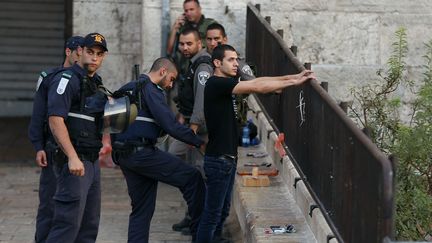 Des policiers isra&eacute;liens contr&ocirc;lent un homme dans J&eacute;rusalem-Est, mardi 13 octobre 2015. (AHMAD GHARABLI / AFP)