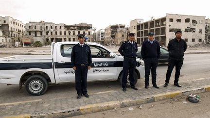 Des policiers libyens prennent la pose, le 15 février 2018, devant le palais de justice détruit de la ville de Benghazi, d'où étaient parties les premières manifestations contre le régime de l'ancien et défunt guide de la Jamahiriya libyenne, Mouammar Kadhafi. (Abdullah DOMA/AFP)