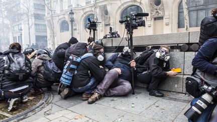 Des journalistes se mettent à l'abri, le 8 décembre 2018 à Paris. (YANN CASTANIER / HANS LUCAS / AFP)