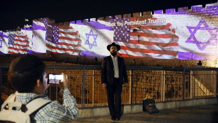 Un enfant prend son père en photo devant les drapeaux américain et israélien projetés sur les murs de la vieille ville de Jérusalem et un message disant "merci président Trump", au soir de l'inauguration de la nouvelle ambassade américaine, le 14 mai 2018. (AMMAR AWAD / REUTERS)