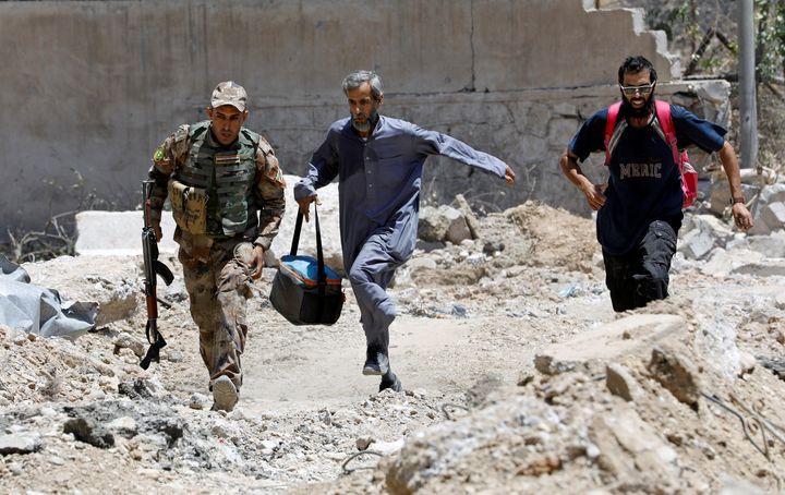 Un soldat irakien et des civils courent pour éviter les balles des snipers de l'Etat islamique, le 15 juin 2017, à Mossoul (Irak).&nbsp; (ERIK DE CASTRO / REUTERS)