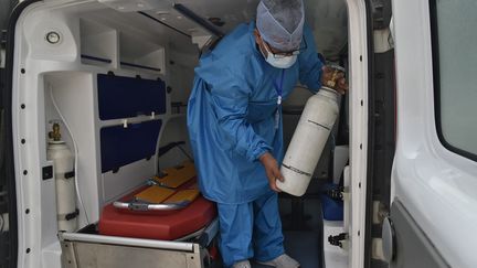 Un médecin Algérien récupère des bouteilles d'oxygène données pour les malades du Covid à Blida le 28 juillet 2021. (RYAD KRAMDI / AFP)