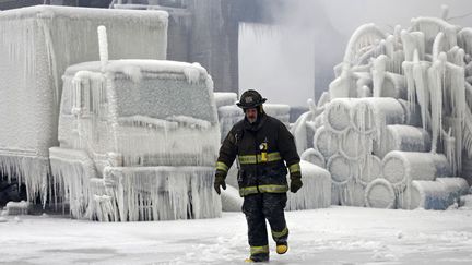 Un pompier marche devant un entrep&ocirc;t recouvert de glace apr&egrave;s avoir &eacute;t&eacute; ravag&eacute; par un spectaculaire incendie&nbsp;&agrave; Chicago (Illinois, Etats-Unis), le 23 janvier 2013. (JOHN GRESS / REUTERS)