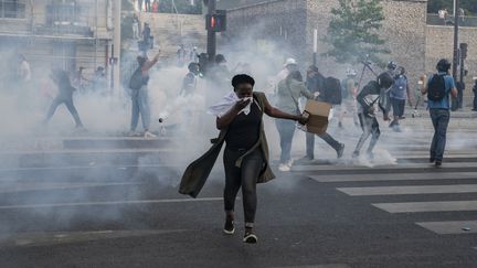 Une femme s'éloigne du gaz lacrymogène libéré&nbsp;par les forces de l'ordre près du Tribunal de Paris après la manifestation du comité Vérité et Justice pour Adama Traoré, le 2 juin 2020, quelques jours après le meurtre de&nbsp;l'Afro-Américain George Floyd. (ANTONI LALLICAN / HANS LUCAS / AFP)