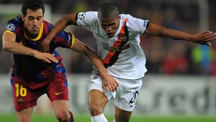 Douglas Costa (Shakhtar) à la lutte avec Busquets (Barça) lors du match aller (LLUIS GENE / AFP)