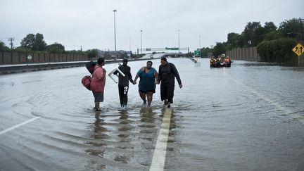 Des habitants de Houston marchent sur une autoroute inondée, le 27 août 2017 à Houston, au Texas (Etats-Unis). (BRENDAN SMIALOWSKI / AFP)