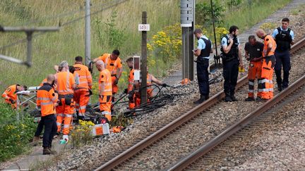 Des employés de la SNCF et des gendarmes français inspectent les lieux d'une attaque sur le réseau ferroviaire à grande vitesse à Croisilles, (Pas-de-Calais), le 26 juillet 2024. (DENIS CHARLET / AFP)