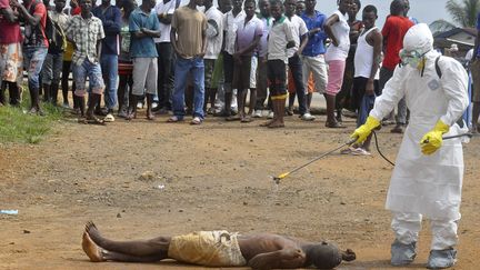 Un membre du personnel m&eacute;dical asperge de d&eacute;sinfectant le cadavre d'un homme suspect&eacute; d'&ecirc;tre mort d'Ebola, &agrave; Monrovia (Liberia), le 4 septembre 2014. (ABBAS DULLEH / AP / SIPA)