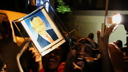 Des Sud-africains brandissent le portrait de Nelson Mandela, &agrave; Johannebourg, le 6 d&eacute;cembre 2013. Des chants et des dans s'improvisent pour rendre hommage &agrave; "Madiba". (ALEXANDER JOE / AFP)