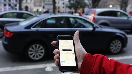 Un client consulte sur son t&eacute;l&eacute;phone son application Uber &agrave; Washington le 25 mars 2015. (ANDREW CABALLERO-REYNOLDS / AFP)