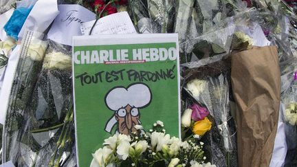 Le Une du Charlie Hebdo du 14 janvier 2015 au milieu des fleurs déposées devant le siège de l'hebdomadaire
 (JOEL SAGET / AFP)