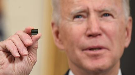 Le président des États-Unis Joe Biden montre une puce électronique le 24 février à la Maison Blanche, lorsqu'il annonce un décret visant à réduire la tension mondiale sur le marché des composants électroniques. (SAUL LOEB / AFP)