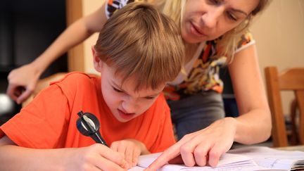 Une mère fait faire des devoirs à son fils. Photo d'illustration. (PHILIPPE TURPIN / MAXPPP)