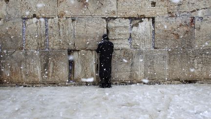 Un homme prie sous la neige devant le Mur des Lamentations &agrave; J&eacute;rusalem (Isra&euml;l), le 10 janvier 2013. (DARREN WHITESIDE / REUTERS)