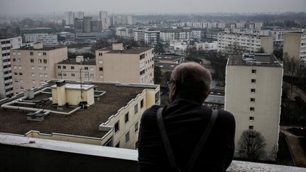 Un habitant de Vaulx-en-Velin regarde&nbsp;par sa fenêtre les grands ensembles de la commune de la banlieue est de Lyon (Rhône), en 2017. Photo d'illustration. (JEFF PACHOUD / AFP)