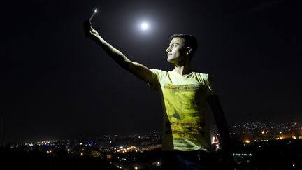 Rouge ou pas, cette super Lune etait un &eacute;v&eacute;nement &agrave; ne pas rater pour de nombreux terriens, comme cet Afghan qui en profite pour immortaliser le moment avec un selfie, &agrave; Kaboul (Afghanistan). (WAKIL KOHSAR / AFP)