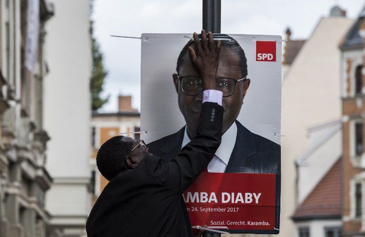 Karamba Diaby, en campagne pour le scrutin de 2017, installe une affiche dans une rue de Halle dans le Land de Saxe-Anhalt (est de l'Allemagne) le 6 septembre 2017. (JOHN MACDOUGALL / AFP)