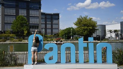 Une jeune femme devant les lettres "Pantin" le long du Canal de l'Ourcq, le 30 juillet 2022, à Pantin (Seine-Saint-Denis). (JULIEN DE ROSA / AFP)