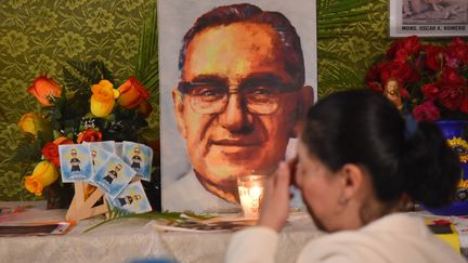 Une femme se signe devant le portrait de l'archevêque du Salvador, Oscar Romero à&nbsp;Ciudad Barrios (Salvador), le 14 octovre 2018. (OSCAR RIVERA / AFP)