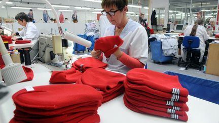 Dans l'usine d'Armor Lux, &agrave; Quimper, une employ&eacute;e confectionne des bonnets rouges (Finist&egrave;re), le 31 octobre 2013. (FRED TANNEAU / AFP)