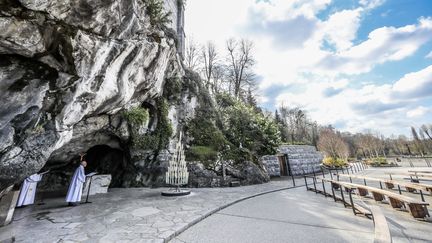 Des chapelains prient dans la&nbsp;grotte vide du sanctuaire de Lourdes, le 21 mars 2020. (LE DEODIC DAVID / MAXPPP)