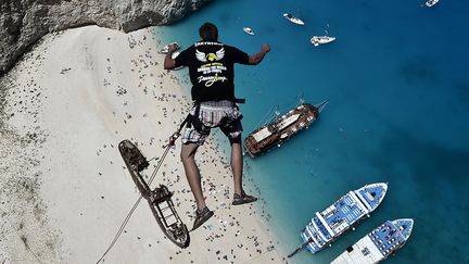 Un jeune homme pratique une forme extr&ecirc;me de saut &agrave; l'&eacute;lastique au-dessus de la page Navagio (Gr&egrave;ce), le 23 juin 2014. (LOUISA GOULIAMAKI / AFP)