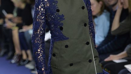 Les vêtements ajourés par des découpes au laser, tendances marquantes de cette saison, étaient présentes dans la collection de la marque japonaise Sacai, lancée en 1999 par la créatrice Chitose Abe. Les cols en général fermés et très stricts contrastaient avec des modèles plus osés. La collection décline la veste militaire vert olive, parfois agrémentées de dentelles et de transparences pour plus de féminité, et fait une large part aux imprimés bleu, rouge et blanc.  "J'ai voulu jouer à mélanger l'uniforme militaire avec la petite robe noire", explique Chitose Abe. Également vues sur d'autres défilés, les sandales aux semelles épaisses étaient très présentes, de même que les volants de style flamenco.
 (MIGUEL MEDINA / AFP)