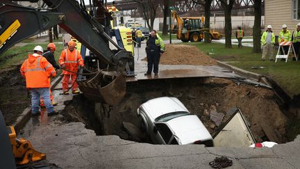 Les secours s'organisent &agrave; Chicago (Illinois, Etats-Unis), le 18 avril 2013. Un trou d'environ 4,5 m&egrave;tres de profondeur est apparu dans la chauss&eacute;e dans une banlieue du sud de la ville. Un camion et deux voitures y sont tomb&eacute;s. (SCOTT OLSON / GETTY IMAGES NORTH AMERICA / AFP )