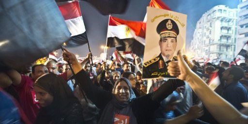 Des Egyptiens manifestent leur joie le 3 juillet 2013 place Tahrir au Caire après la déposition par l'armée du président islamiste Mohamed Morsi. Les manifestants brandissent notamment un portrait du nouvel homme fort du pays, Abdel Fattah al-Sissi. (AFP - Khaled Desouki)