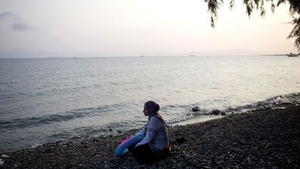 Sur une plage de l'île de Kos, une réfugiée syrienne regarde la mer Egée après avoir fait la traversée entre la Turquie et la Grèce, le 10 août 2015. La Grèce a été totalement débordée par le nombre de migrants et les accueille dans des conditions «totalement honteuses», selon un fonctionnaire de l'ONU. (ANGELOS TZORTZINIS / AFP)